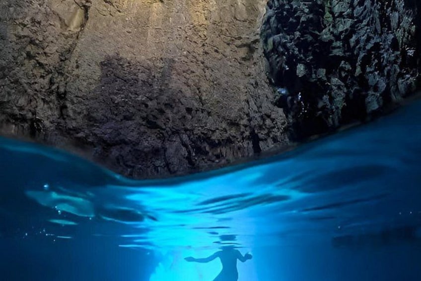 An underwater cave with rocky walls and clear blue water. 3