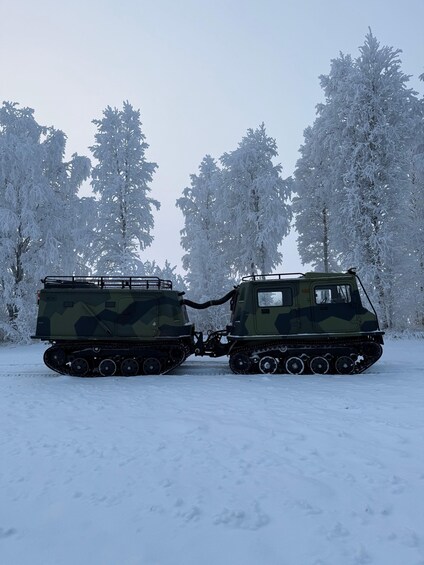 Kaksi maastokuvioin maalattua sotilasajoneuvoa lumisessa metsässä. 4
