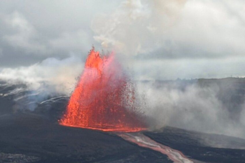 Una erupción volcánica con lava fluyendo y vapor ascendiendo. 1