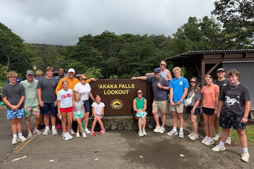 A group of people standing in front of a sign that reads 'Akaka Falls Lookout.' 4