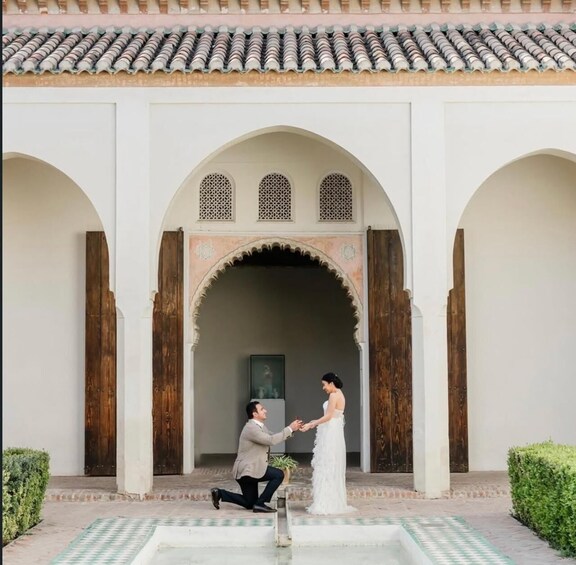 Ein Mann macht ihr in einem Innenhof mit Bögen und einem Ziegeldach einen Heiratsantrag. 2