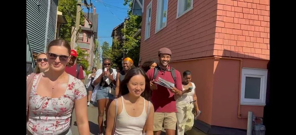 A group of people walking down a street lined with buildings. 1