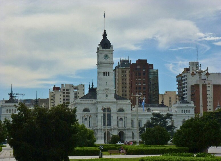 A historic building with a clock tower, surrounded by modern high-rise buildings and greenery. 4