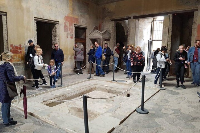 A group of people standing in a courtyard with a central open area, possibly a historical site or museum. 1