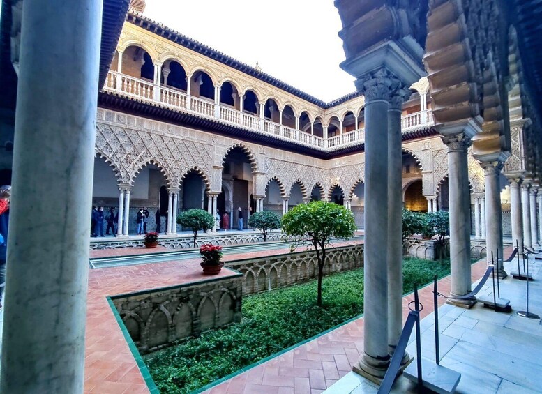 An ornate courtyard with arches, columns, and a central garden. 1