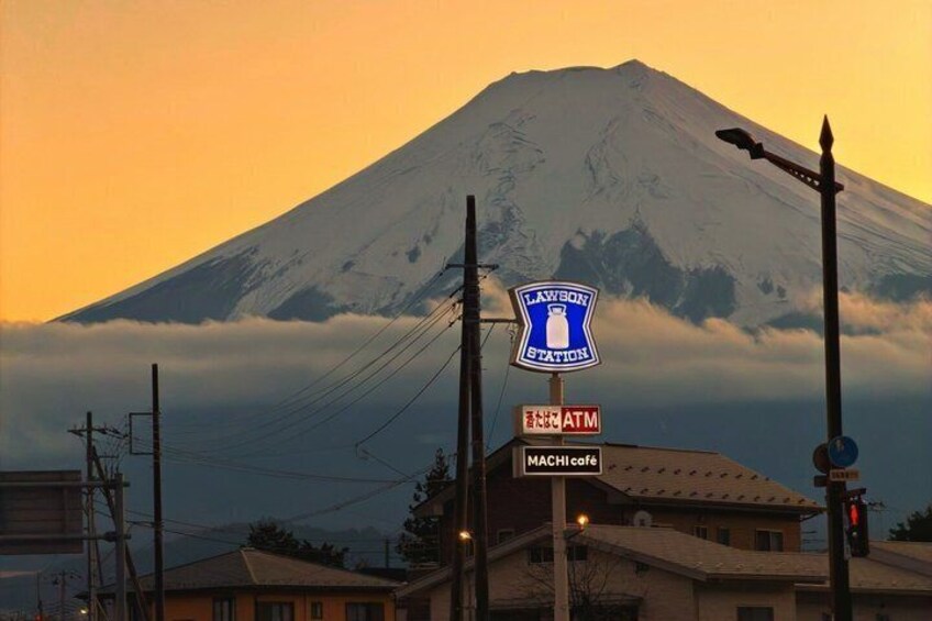 Letrero de Lawson Station, un cajero automático y un letrero de café MACHI con una montaña nevada al fondo. 3