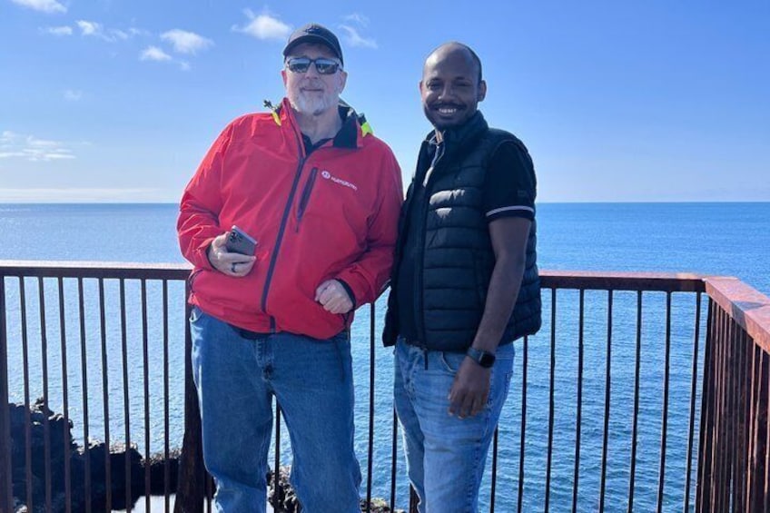 Two people standing on a deck with a railing, overlooking a body of water. 4