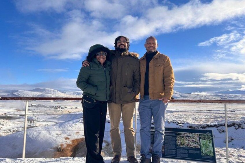 Three people standing on a snowy landscape with a clear sky. 4