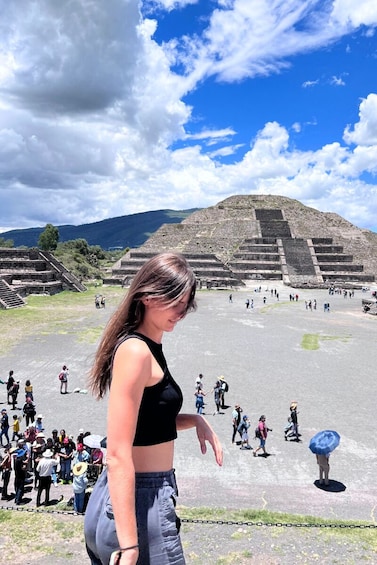 Henkilö seisoo suuren pyramidin edessä, ja taustalla näkyy turisteja. 1