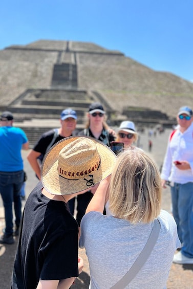 Ryhmä ihmisiä seisomassa suuren pyramidin muotoisen rakennelman edessä. 5