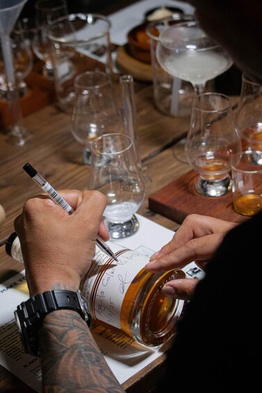 A person writing on a wine bottle label. 5