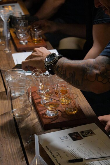 A person pouring a drink into a glass on a wooden tray with measuring jugs. 2