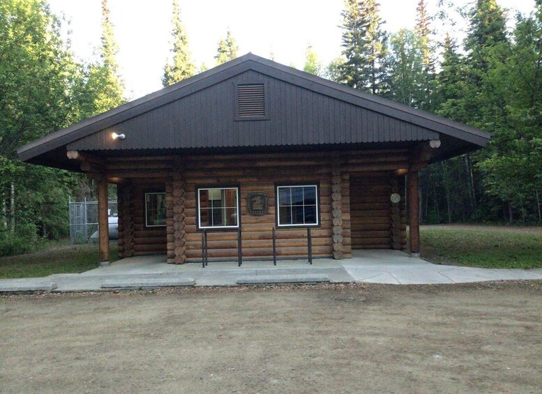 A rustic log cabin with a metal roof, two windows, and a plaque on the wall. 4