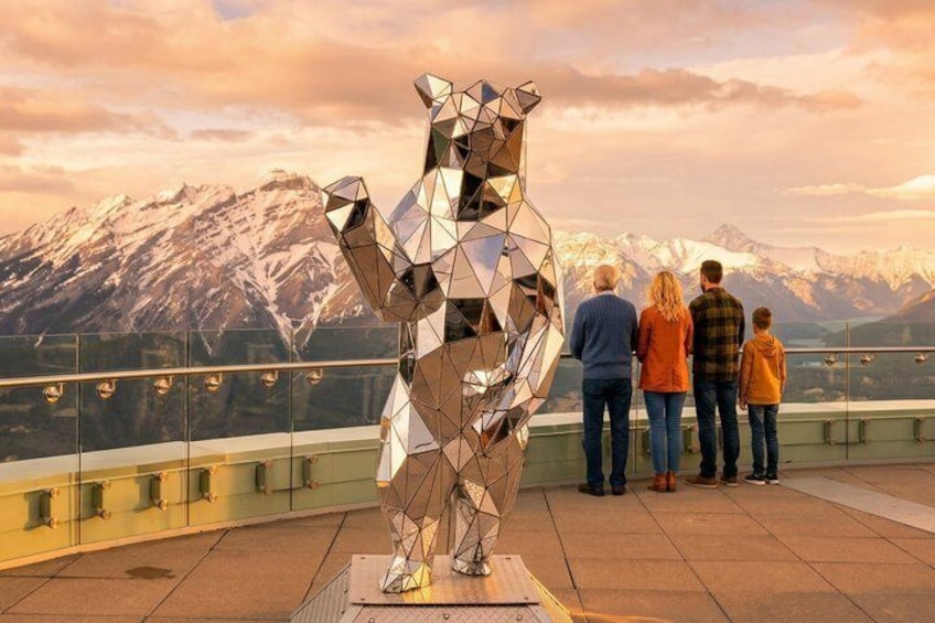 En skulptur av en björn, gjord av metall, placerad på ett hustak med ett berg i bakgrunden. 2