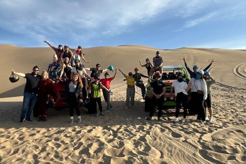 Eine Gruppe von Personen posiert mit einem Geländewagen in einer Wüstenlandschaft. 1