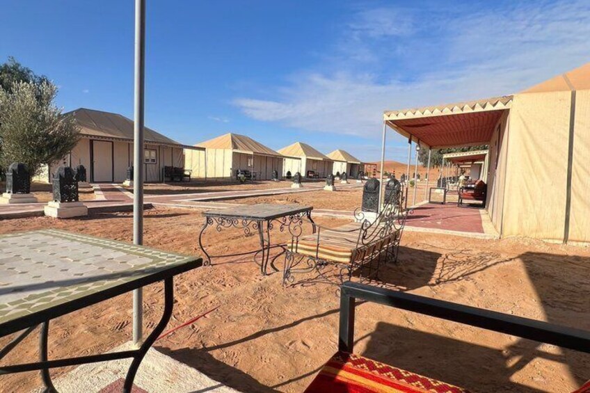 A desert campsite with tents, a table, and a covered area. 5