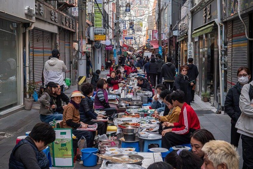 A street market with people sitting at tables, eating and socializing. 2