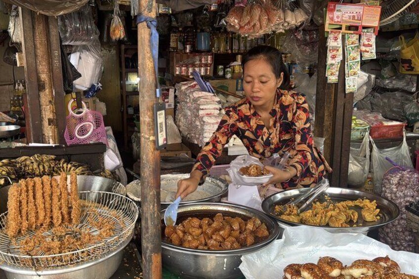 A street food vendor preparing food at a stall with various cooking utensils and ingredients. 1