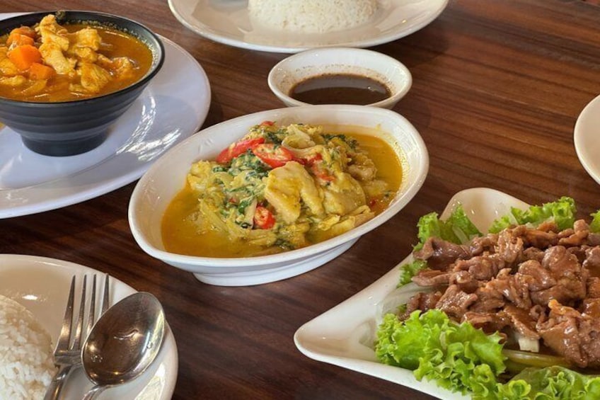 A table with various dishes including curry, rice, and meat. 5