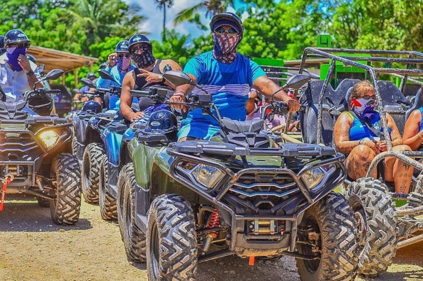 A group of people on ATVs in a line, with a tropical background. 2