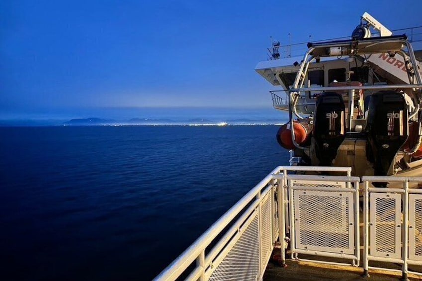 A boat with two outboard motors, a metal railing, and a view of the ocean and distant shoreline. 5
