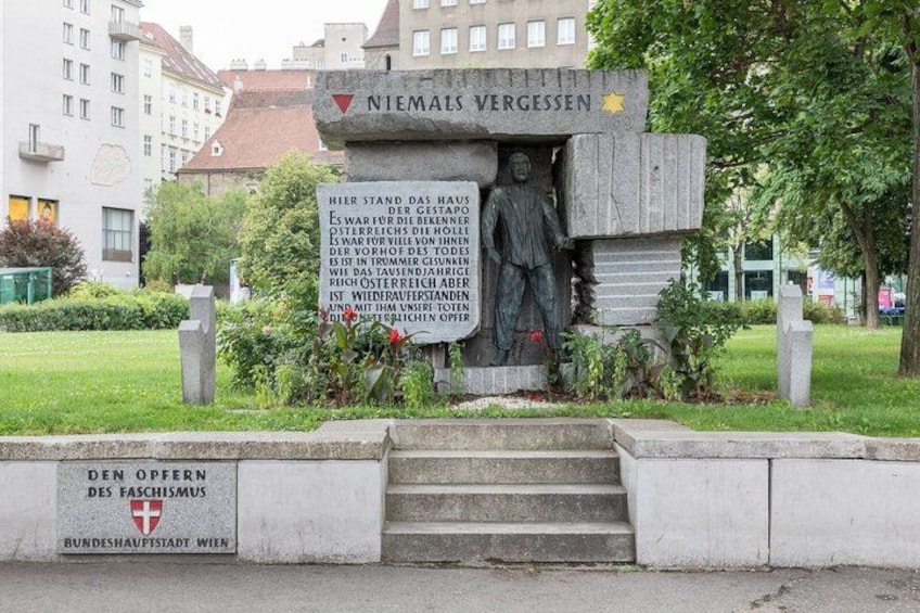 Ein Gedenkdenkmal mit einer Tafel, umgeben von Stufen und Grünpflanzen. 4