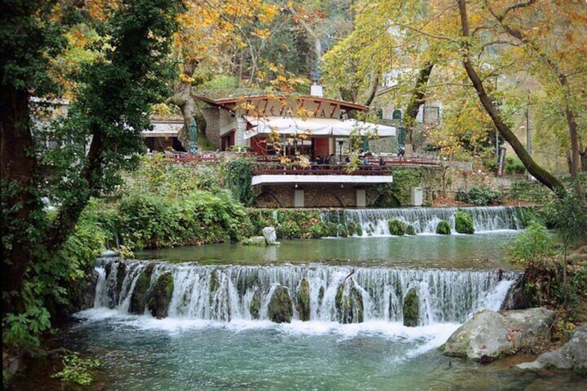 A waterfall, a pond, and a building with a terrace. 1