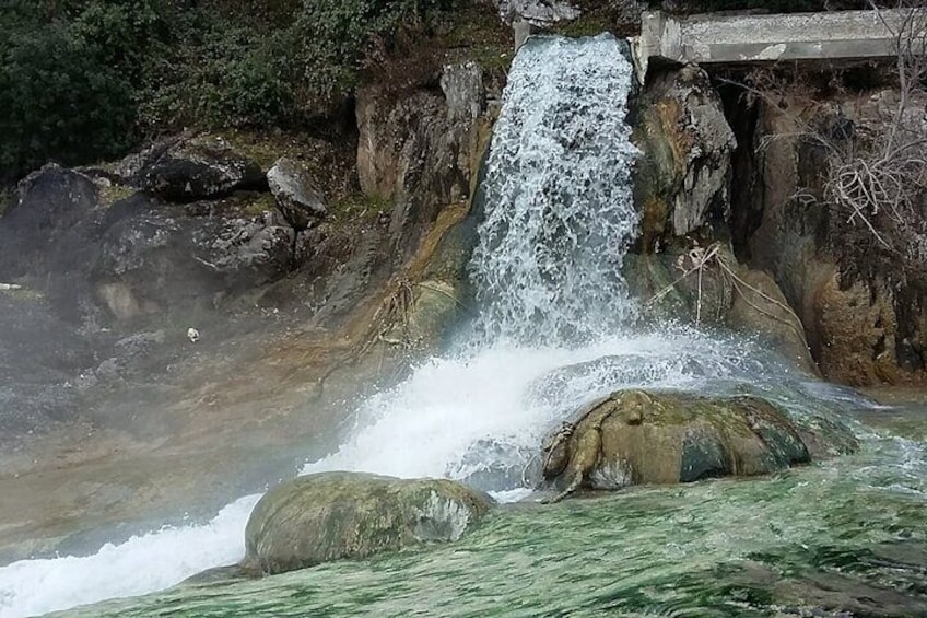 A waterfall cascading over rocks into a pool, surrounded by greenery. 2