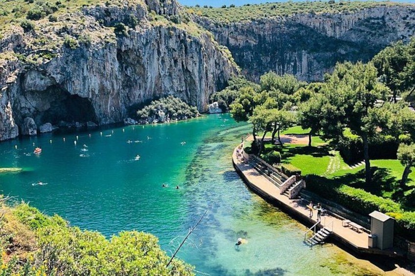 Une rivière aux eaux d’un bleu limpide, bordée de falaises, avec une zone aménagée pour la baignade et un parc arboré. 1