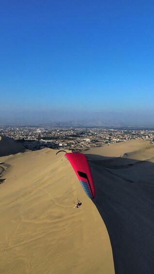 A person paragliding over a desert landscape with a city in the distance. 4