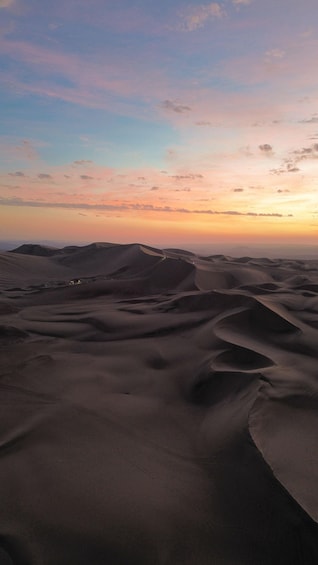 A desert landscape with sand dunes and a sunset sky. 1