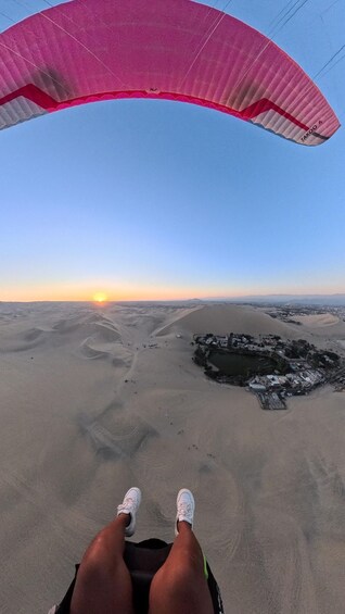 A person paragliding over a desert landscape with a sunset in the background. 4
