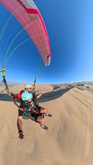 A person paragliding over a desert landscape. 5