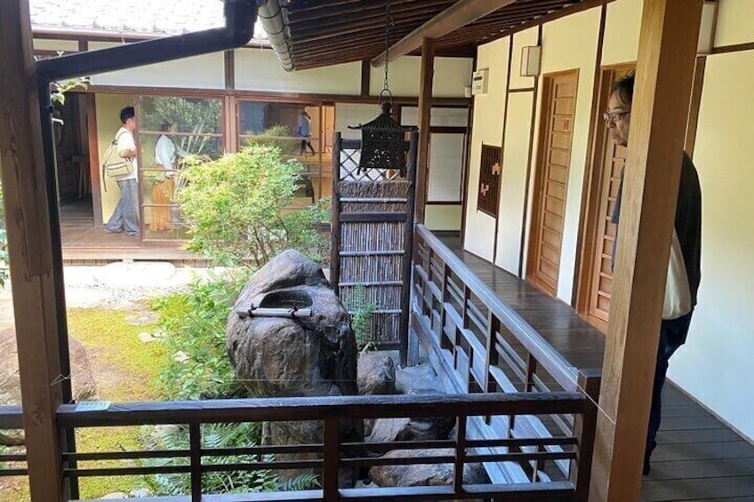 A traditional Japanese building with a wooden deck, a stone lantern, and a garden with rocks and plants. 4