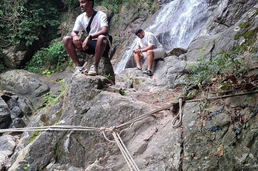 Two people sitting on rocks near a waterfall. 4
