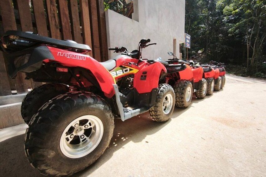 A row of red quad bikes parked in front of a building. 5