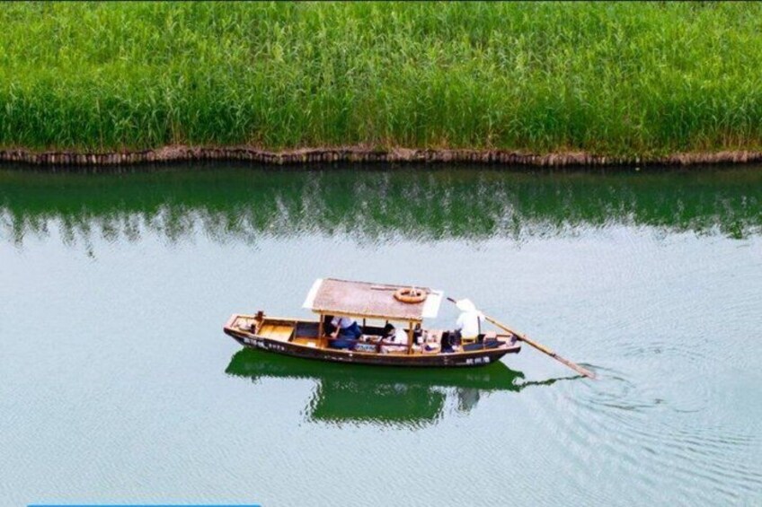 Ein Kahn mit Verdeck auf einem ruhigen Fluss, umgeben von üppiger Vegetation. 2