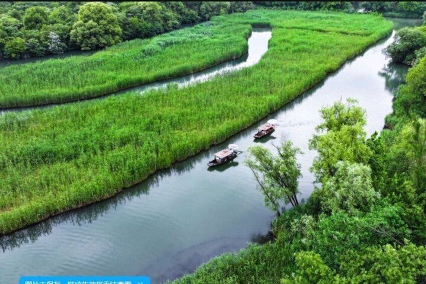 Ein Fluss schlängelt sich durch saftig grüne Felder, auf dem Wasser sind Boote unterwegs. 3