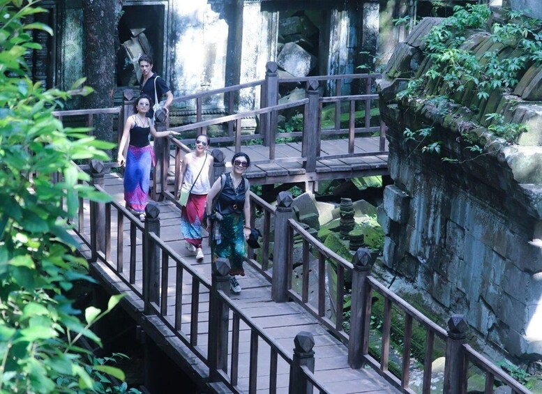 A wooden bridge with railings, surrounded by lush greenery and ancient stone structures. 5