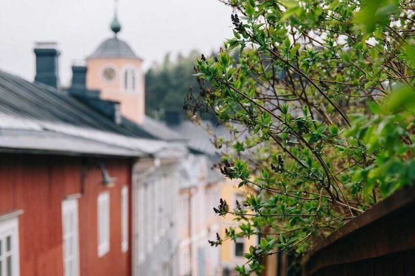A red building with a clock tower, a tree with green leaves, and a blurred background of other buildings. 3