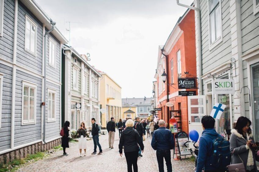 A cobblestone street lined with historic buildings, a museum sign, and a blue cross flag. 4