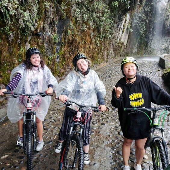 Three cyclists on a rocky path with a waterfall in the background. 2