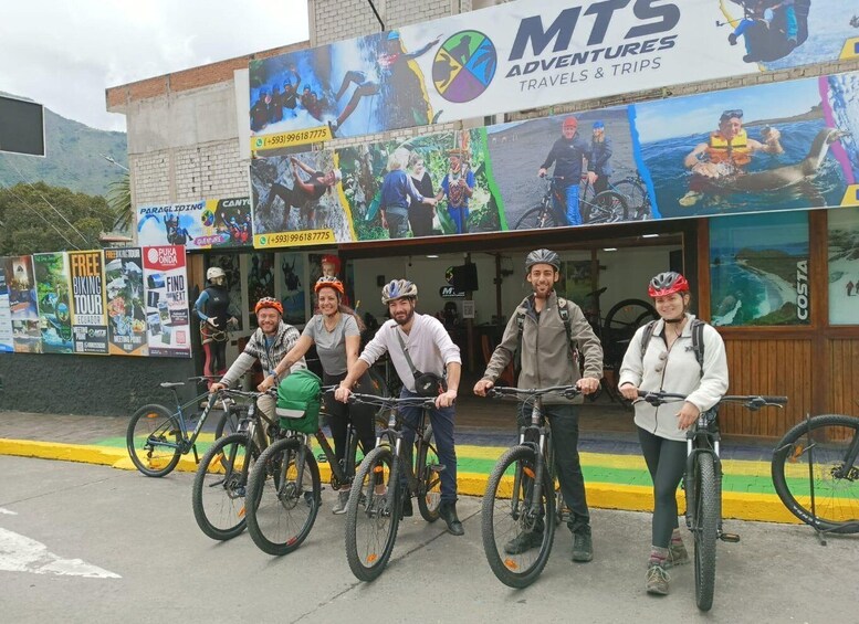 A group of people on bicycles in front of a travel agency with adventure posters. 1