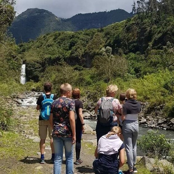 A group of hikers on a trail with a waterfall in the background. 4