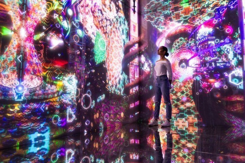 A person standing in a room with a vibrant, colorful digital display. 1