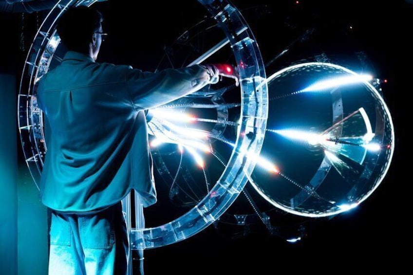 A person operating a large, illuminated circular structure. 3
