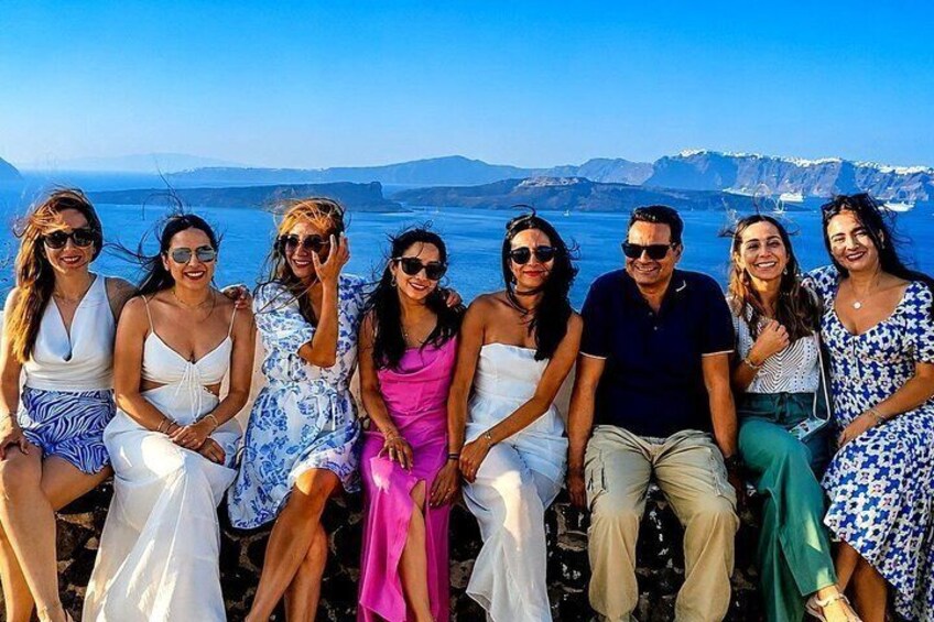 A group of people sitting on a rocky outcrop with a coastal landscape in the background. 4