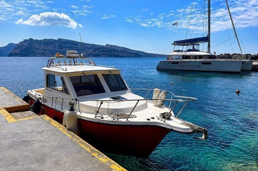 A red and white boat docked at a pier with clear blue water and a mountainous backdrop. 2