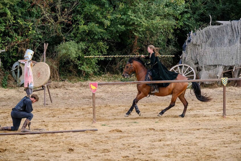 A person riding a horse in an outdoor arena with a hay bale and a flag in the background. 3