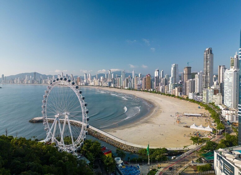 A coastal cityscape with a large Ferris wheel, a beach, and high-rise buildings. 5